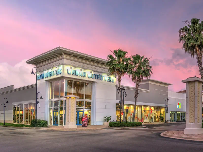 Tenant Rep Retail shops with glowing signs at dusk.